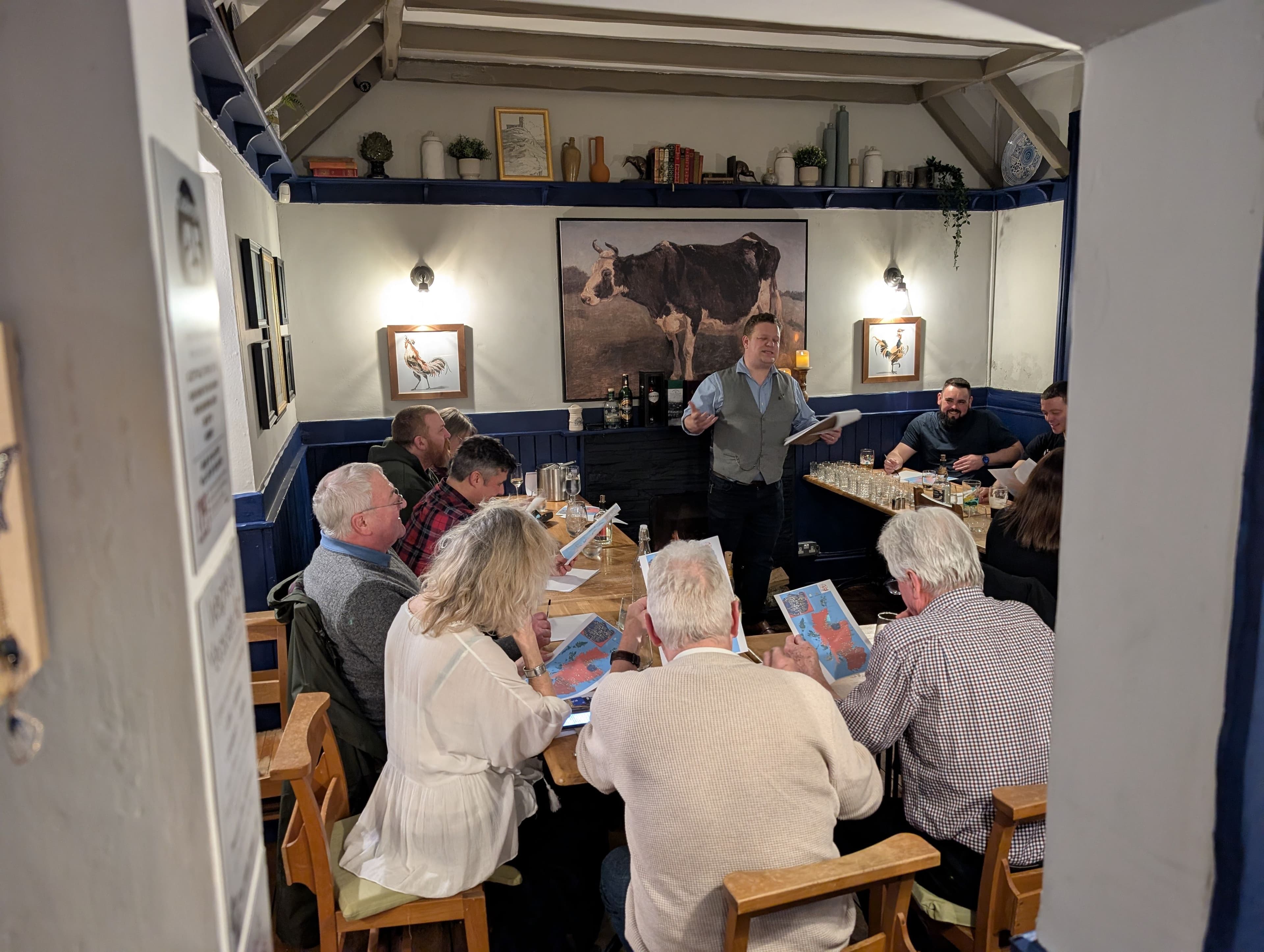 whisky tasting event with groups of people sat at tables whilst the host explains all about the whisky