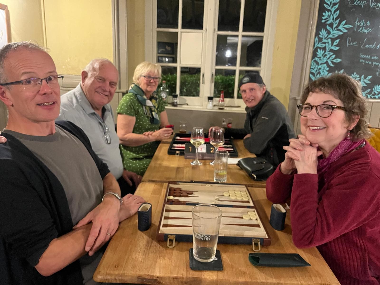 A group of people sat in a pub playing backgammon